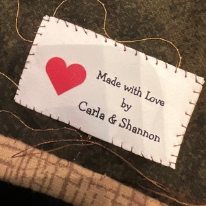 May include: White fabric label with a red heart and the text "Made with Love by Carla & Shannon".