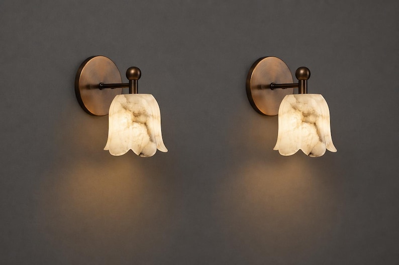 Modern brass wall sconce set with alabaster stone shade, minimalist bedroom wall lighting on grey background Mid century brass wall lights with white alabaster tulip shades, luxury wall sconce pair for bedroom decor Set of two brass wall sconces with natural alabaster shades, elegant modern wall lighting fixture Minimal brass wall lamps with alabaster shade, bedside wall lighting pair on neutral grey wall Luxury brass wall sconce pair with alabaster tulip glass shade, modern wall lighting.