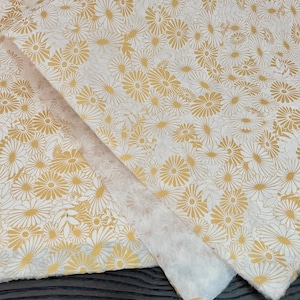 K&ouml;nnte beinhalten: Wei&szlig;es Seidenpapier mit einem goldenen Blumenmuster. Das Muster zeigt kleine, stilisierte G&auml;nsebl&uuml;mchen.