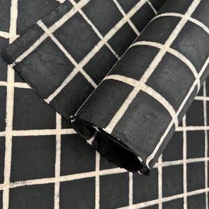 May include: Black and white checkered wrapping paper rolled up. The paper has a textured surface.