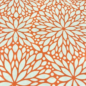 May include: Orange fabric with a white floral pattern. The pattern features a repeating design of stylized flowers with rounded petals and small circles.
