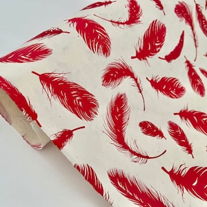 May include: Red feather pattern wrapping paper. The paper is cream colored with a repeating pattern of red feathers.