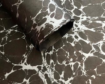 May include: A roll of black and white marbled paper. The paper has a swirling pattern of white on a dark grey background.