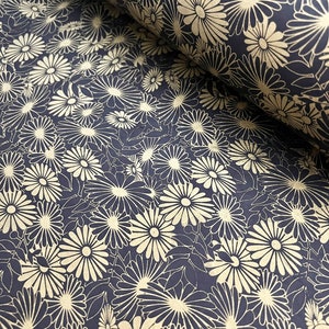 K&ouml;nnte beinhalten: Ein schwarzes und goldenes Geschenkpapier mit floralem Muster und einem sich wiederholenden Design aus stilisierten Blumen. Das Papier ist aufgerollt und das Muster ist sowohl auf der Vorder- als auch auf der R&uuml;ckseite der Rolle sichtbar.