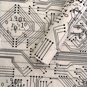 May include: White paper with a black circuit board design, featuring lines, circles, and binary code. A rolled section of the paper reveals the pattern's continuity. The design is reminiscent of computer technology.