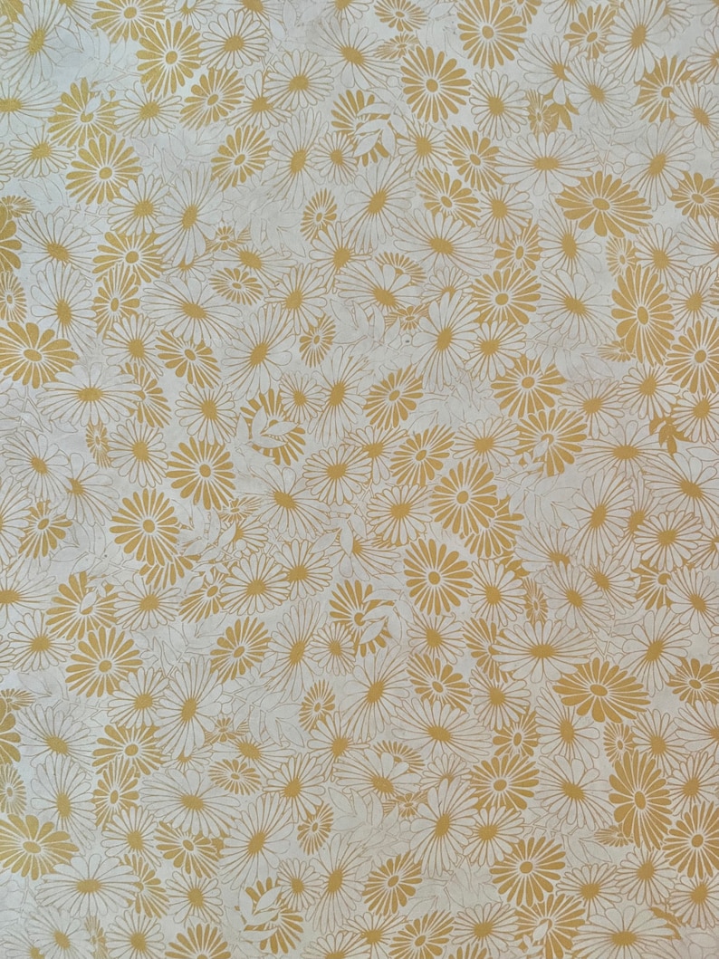 K&ouml;nnte beinhalten: Ein wei&szlig;er Hintergrund mit einem sich wiederholenden Muster aus goldenen G&auml;nsebl&uuml;mchen.