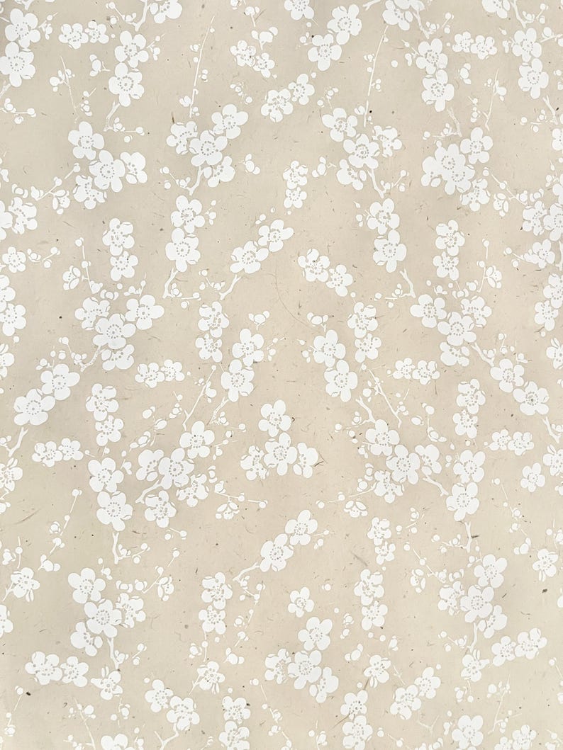 Puede incluir: Un fondo beige con un patr&oacute;n floral blanco. Las flores son peque&ntilde;as y delicadas, y est&aacute;n dispuestas en un patr&oacute;n repetitivo.