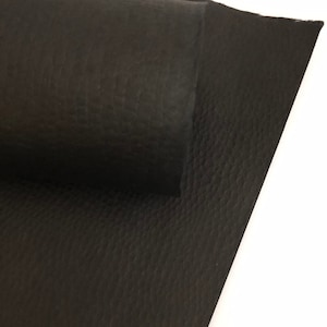May include: Close-up of black leather material with a textured surface. The leather is folded and rolled, revealing the underside. The material has a matte finish and is suitable for various crafting projects.