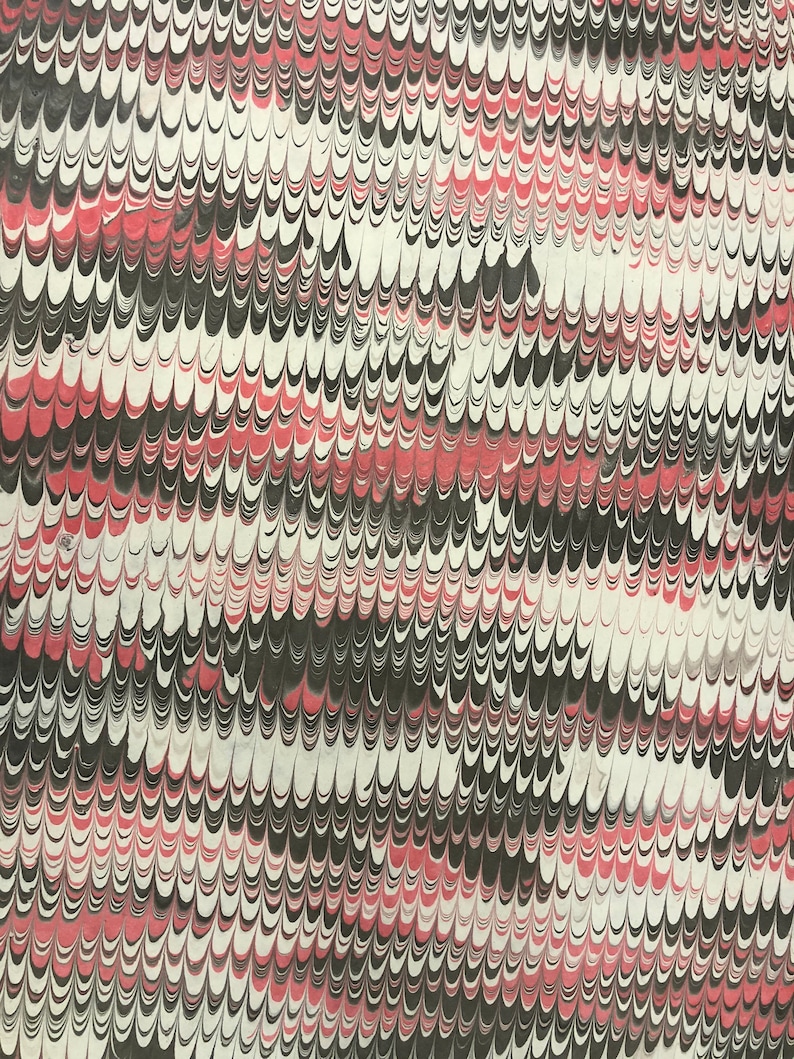 May include: A sheet of paper featuring a marbled pattern with repeating wave-like shapes in black, white, and muted red. The design consists of vertical columns of interlocking, curved lines that create a dense, textured visual effect across the surface.