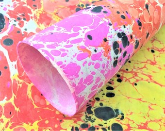 May include: A roll of marbled paper with pink, orange, yellow, and black swirls. The paper is rolled up and the end is visible.