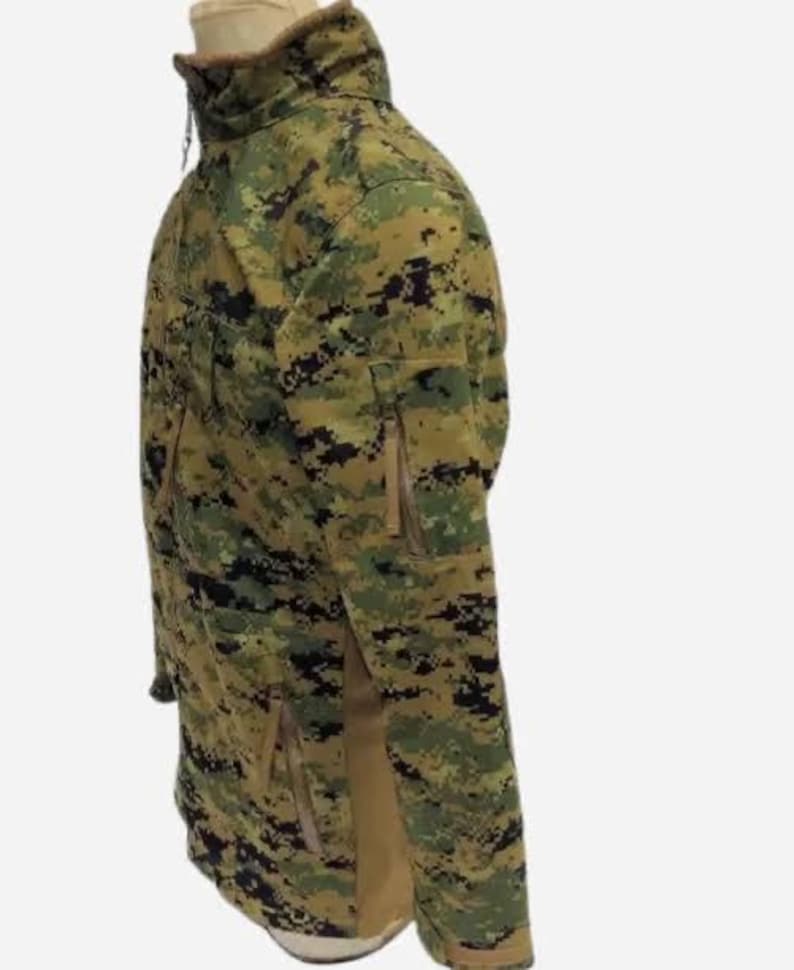 May include: A camouflage jacket in shades of green, brown, and black. The jacket features a high collar, multiple pockets, and a zipper closure. The fabric has a pixelated pattern, typical of military-style clothing.