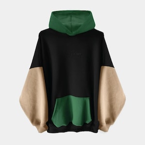 May include: A color-block hoodie in black, tan, and green. The hoodie features a green hood and pocket, with tan sleeves and a black body. The word "SWEETLAWS" is embroidered on the chest. The hoodie has a kangaroo pocket.
