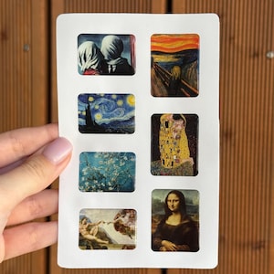 May include: A white card with six rectangular magnets, each displaying a famous artwork. The magnets showcase reproductions of paintings including "The Son of Man", "The Scream", "Starry Night", "The Kiss", "Almond Blossoms", and the "Mona Lisa".