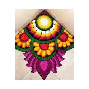 Könnte beinhalten: Ein farbenfroher, blumenförmiger Teppich mit einem lebendigen Design. Der Teppich hat einen zentralen gelben Kreis, der von konzentrischen Ringen aus Rot, Orange, Gelb und Weiß umgeben ist. Das Design umfasst blütenartige Formen in Rot, Gelb und Lila.