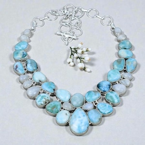 May include: A statement necklace featuring multiple polished, sky-blue and white marbled stones set in silver-toned metal. The design includes a tiered arrangement of rounded, organic-shaped cabochons and a silver chain with a toggle clasp closure.