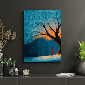 May include: A canvas print depicts a person in a red coat standing under a tree with blue and orange leaves, in a snowy scene. The artwork has a dreamy, illustrative style, evoking a sense of winter and solitude.