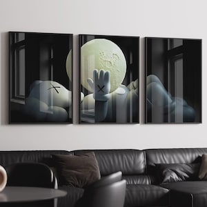 May include: A triptych of framed art prints featuring a cartoon character with an 'X' for eyes, resting near a large moon. The character's gloved hand is raised towards the moon. The artwork is set against a dark, window-lined background.