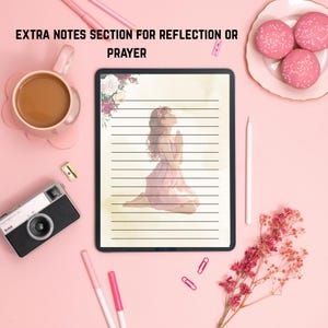 May include: A digital tablet with lined paper and an illustration of a person praying. The tablet is surrounded by a pink background with a coffee cup, camera, pens, and macarons. The text "EXTRA NOTES SECTION FOR REFLECTION OR PRAYER" is at the top.