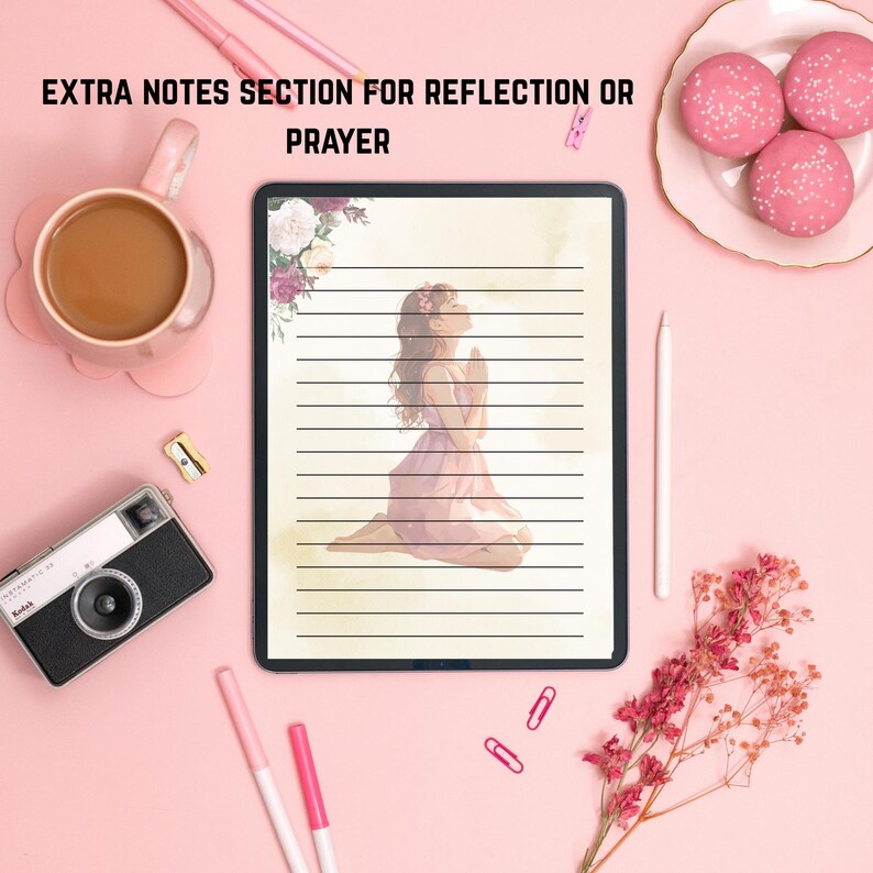 May include: A digital tablet with lined paper and an illustration of a person praying. The tablet is surrounded by a pink background with a coffee cup, camera, pens, and macarons. The text "EXTRA NOTES SECTION FOR REFLECTION OR PRAYER" is at the top.