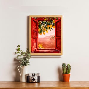 May include: A framed wall art print depicting an open window with bright red shutters looking out onto a landscape with yellow lemons hanging from a tree branch in the foreground and a warm, hazy, reddish-toned horizon in the distance.