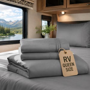 May include: A set of solid gray bed sheets folded on a bed, featuring a light brown rectangular tag with the black text RV QUEEN SIZE. The sheets have a smooth texture and are displayed with a matching gray pillowcase in the background.