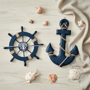 May include: Navy blue nautical decor set featuring a ship's wheel (27.5 cm) and an anchor, both adorned with rope detailing. Seashells are scattered around the objects, creating a coastal theme.