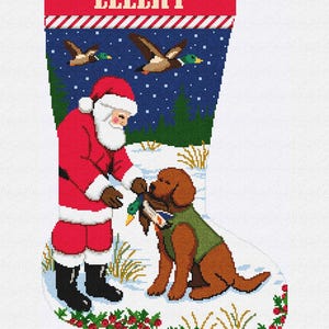 May include: A Christmas stocking featuring a cross-stitch design of Santa Claus interacting with a brown dog wearing a green vest. The scene includes flying ducks, a snowy landscape, and the name ELLERY printed in white on a red top border.