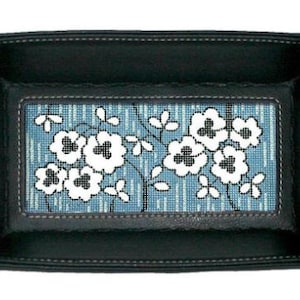 May include: A black leather tray with a blue and white floral design. The tray has a stitched border and a decorative design in the center.