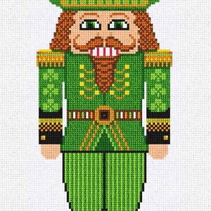 May include: A cross-stitch image of a green nutcracker soldier with a green hat, jacket, and pants. The nutcracker has a brown beard and mustache, and brown boots. The jacket has gold accents and a black belt.