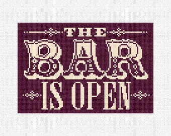May include: Cross-stitch design on a burgundy background with the words "THE BAR IS OPEN" in cream-colored, pixelated letters. The text is framed by decorative lines and flourishes, suitable for bar decor.