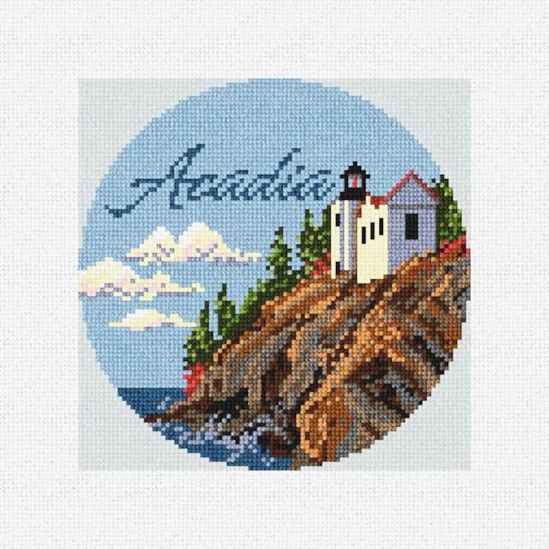 May include: A cross-stitch design featuring a lighthouse on a rocky cliff with the word "Acadia" in cursive script. The scene is set against a blue sky with white clouds.