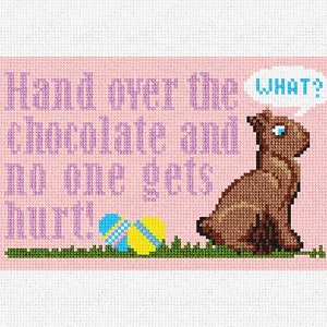 May include: A pink cross-stitch design featuring a brown bunny rabbit with a thought bubble that says "WHAT?" The bunny is sitting on green grass with two colorful Easter eggs. The text above the bunny reads "Hand over the chocolate and no one gets hurt!"