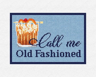 May include: Cross-stitch design featuring an Old Fashioned cocktail with an orange peel and cherry garnish. The text "Call me Old Fashioned" is stitched in a dark blue font against a light blue background.