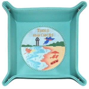May include: Turquoise leather tray with a circular embroidered patch depicting a beach scene with a lighthouse, a bird, and the text "Turks and Caicos".