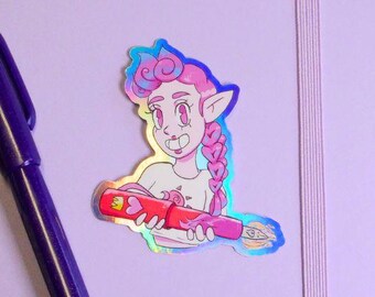 May include: A lilac notebook with a matching pen and a holographic sticker of a cartoon character holding a red pen. The notebook has a vertical elastic band and a rounded corner.