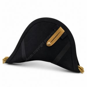 Puede incluir: Un sombrero bicornio negro con adornos y borlas doradas. El sombrero presenta un ala curvada y una banda dorada decorativa en el lateral. Probablemente sea una pieza histórica o de disfraz.