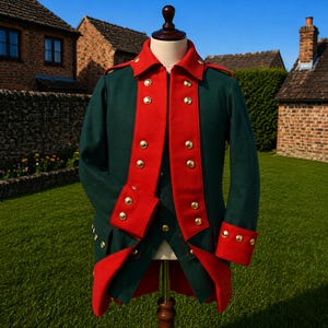 Könnte beinhalten: Eine grüne Militärjacke mit roter Verzierung und goldenen Knöpfen. Die Jacke wird auf einer Schaufensterpuppe präsentiert. Die Jacke hat einen hohen Kragen und rote Verzierungen an der Vorderseite und an den Manschetten.
