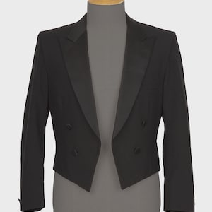 May include: A black tuxedo jacket with a satin lapel and double-breasted button closure. The formal wear jacket is displayed on a mannequin. The jacket has two front pockets and a tailored fit. The jacket is a classic style.