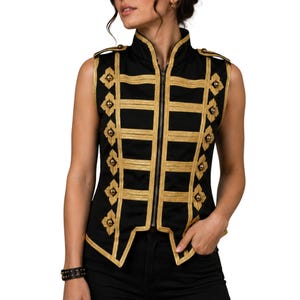 May include: Black sleeveless vest with gold trim and decorative details. The vest has a high collar, a full-length zip, and gold embellishments. The gold trim contrasts with the black fabric, creating a distinctive look. The vest is a stylish garment.
