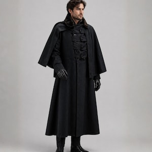 Op de afbeelding: Een lange, zwarte jas met bijpassende cape en handschoenen. De jas heeft een dubbelborstig ontwerp met meerdere knopen en een bontkraag. De outfit is een donkere, gotische stijl.