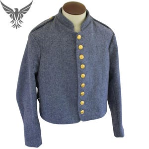 Könnte beinhalten: Blaue Wolljacke mit Stehkragen und goldfarbenen Knöpfen. Die Jacke hat lange Ärmel und Schulterklappen. Die Jacke wird auf einer Schaufensterpuppe präsentiert.