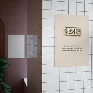 May include: A beige poster with a ticket-style graphic featuring the number 28. The poster includes text that reads, "Took twenty-eight years of blood pumpin' through me to get to this evening with you."
