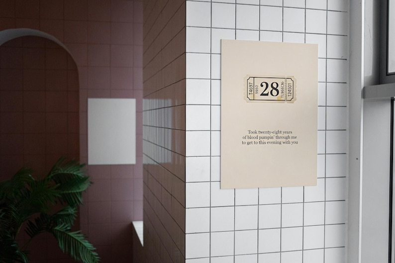 May include: A beige poster with a ticket-style graphic featuring the number 28. The poster includes text that reads, "Took twenty-eight years of blood pumpin' through me to get to this evening with you."