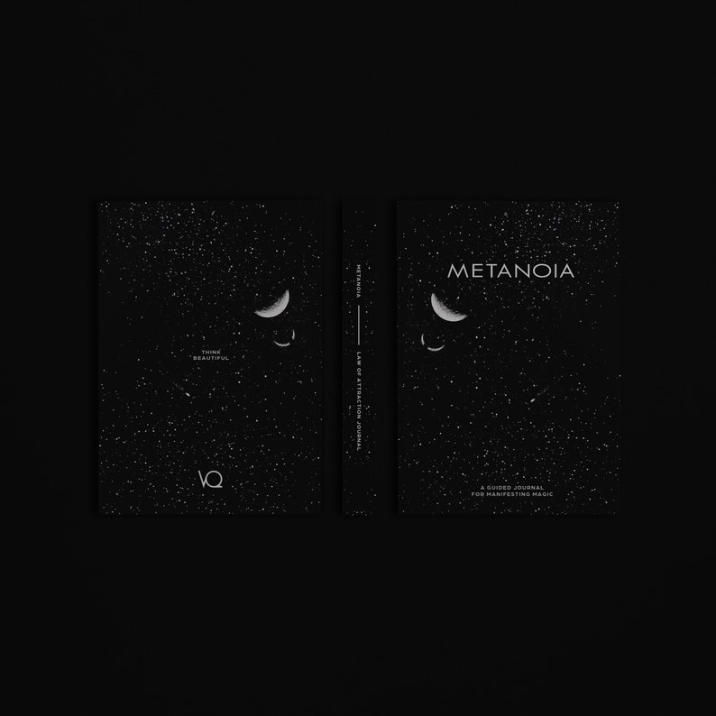 May include: A black journal with the word "METANOIA" on the cover, along with a crescent moon design and scattered white dots. The spine reads "METANOIA LAW OF ATTRACTION JOURNAL." The journal is open, revealing the inside pages.