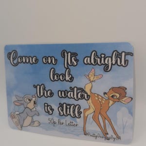 May include: A rectangular card with a blue watercolor background, featuring Bambi and Thumper. The card has the text "Come on, It's alright, look, the water is still". A butterfly is perched on Bambi's tail.