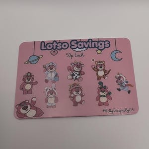 May include: A pink card with the text "Lots Savings" and "50p Each". The card features illustrations of teddy bears in various costumes, including a bunny, cow, and tiger. The card also has a planet, stars, and a crescent moon.