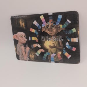 May include: A rectangular card featuring two cartoon characters and colorful socks. The text "£1 Per Sock" is visible. The background is dark with lit candles. The card is on a white surface.