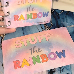 May include: A set of pastel-coloured cards with the text "STUFF the RAINBOW" in a playful font, featuring a rainbow design. The cards are bound with a silver ring. A small die with orange and green circles is also visible.