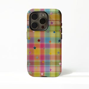 May include: A colorful phone case with a plaid pattern in shades of yellow, pink, blue, and green. The case is adorned with various star shapes in different colors and textures. The phone case has a camera and flash.