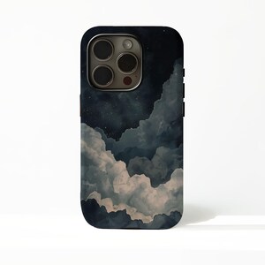 以下が含まれることがあります： 夜空と雲の水彩デザインが施された黒いスマートフォンケース。ケースは濃い青色の縁と光沢のある仕上がりです。デザインには青、グレー、白の色合いが含まれており、夢のような美しさを生み出しています。